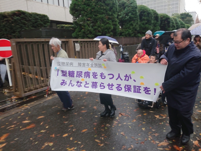 雨の中、横断幕を持って歩く写真