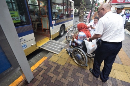 車いすユーザーがアクセシブルなバスのスロープに乗る様子