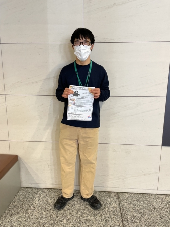 案内チラシを持って立つ、スタッフの古市裕起（ふるいち ゆうき）さん