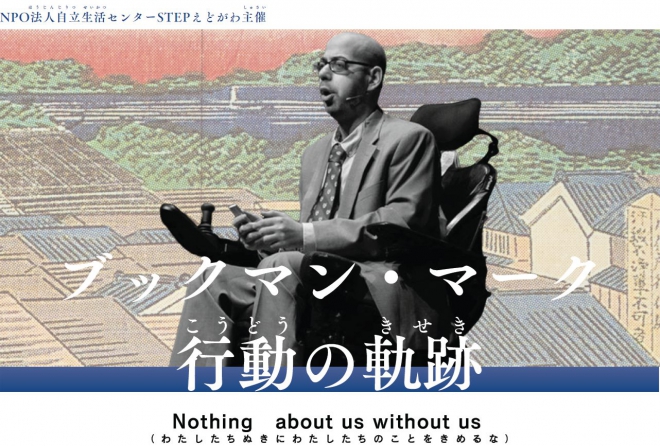 電動車いすに乗るブックマン。ピンマイクをつけて講演をしている様子