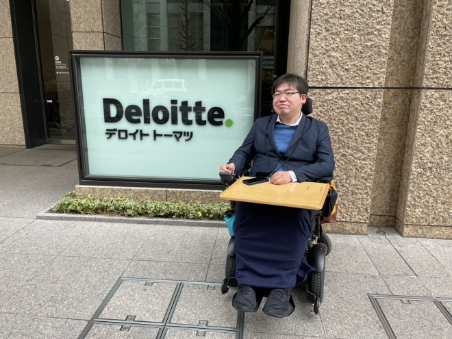 デロイト トーマツ グループのオフィスの前に座る岡本